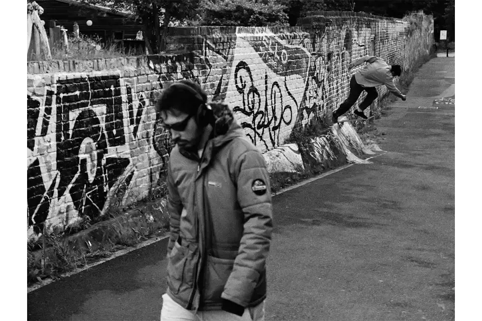Portrait of a man with a skater in the background. 