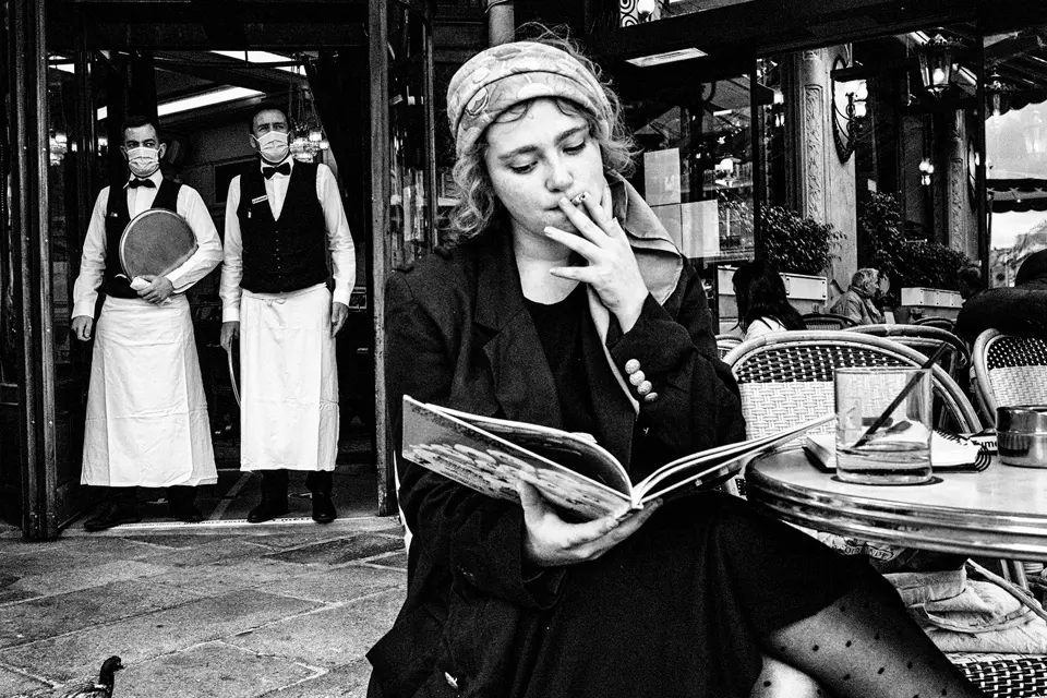 Woman reading a book in a restaurant while smoking a cigarette