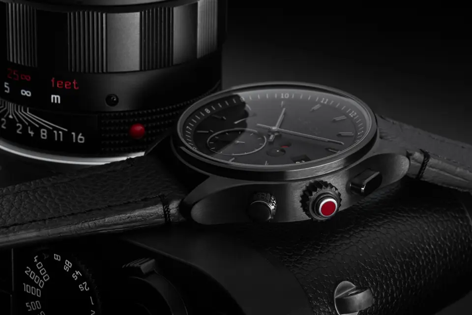 Black leica watch with leica camera behind the watch