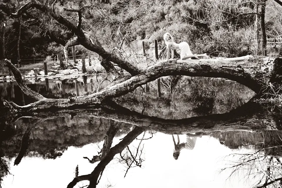 Woman lying on tree trunk by the lake