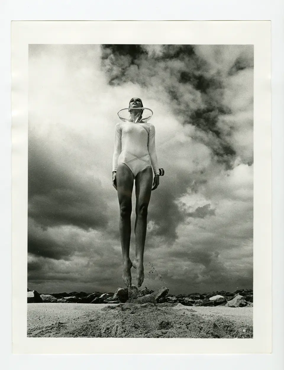 photo of lady jumping on sand wearing white swimwear