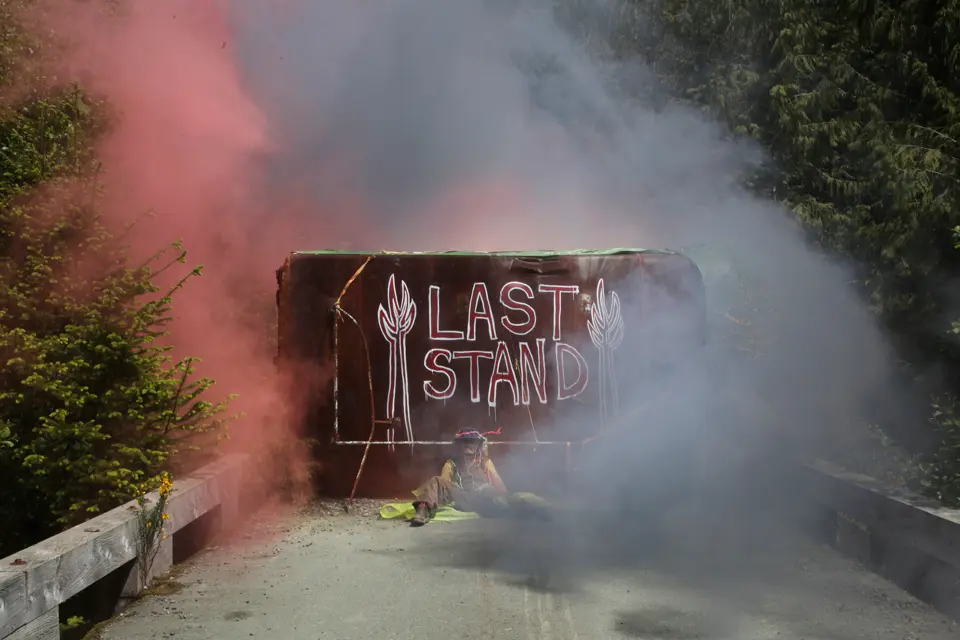 An activist is chained to a bus in the middle of a road over a bridge