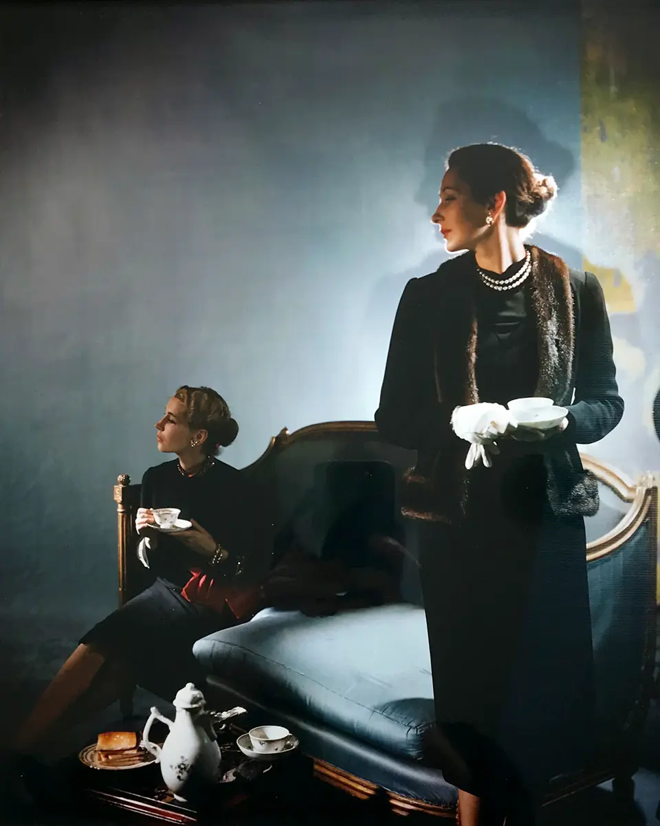 Photo of 2 ladies next to a blue sofa holding cups