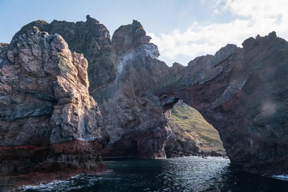 The rugged cliffs, dramatic arch, and interplay of light and shadow.