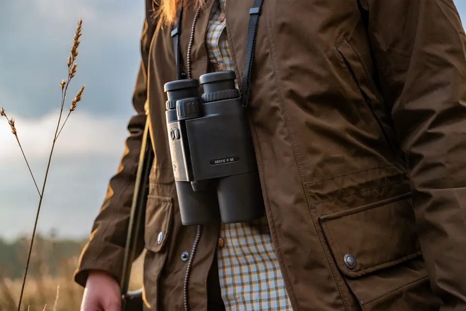 Leica-Geovid-R-SE-hanging-from-the-strap-in-front-of-a-hunter's-upper-body