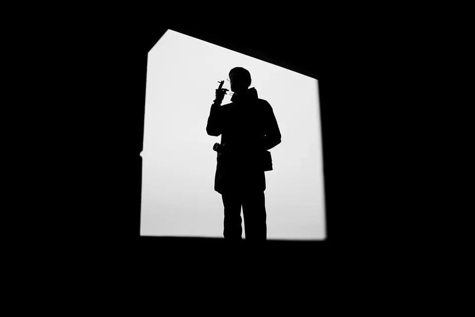 Man in the dark in front of a bright screen.