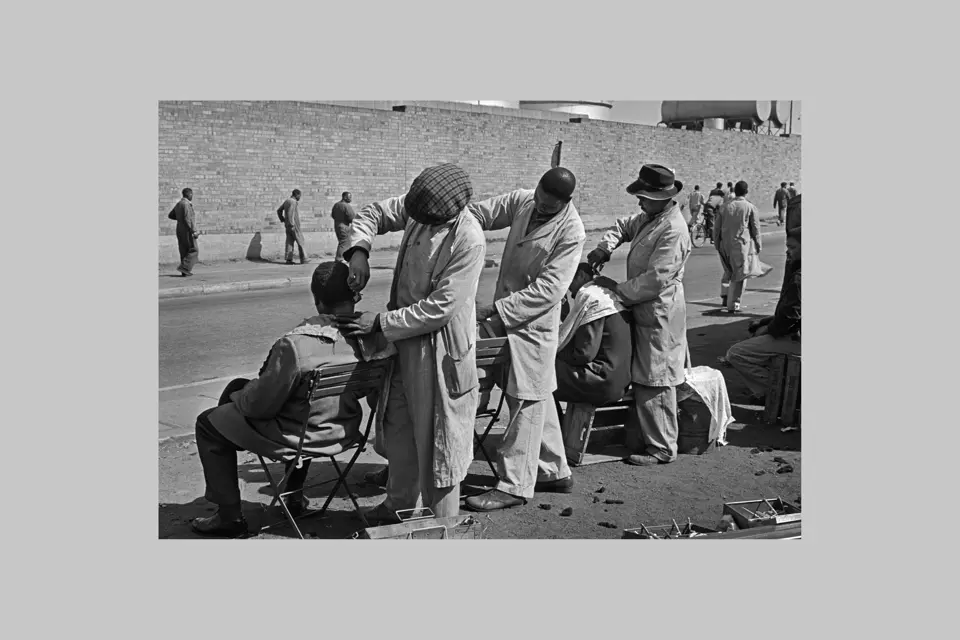 Three man get a haircut next to a street