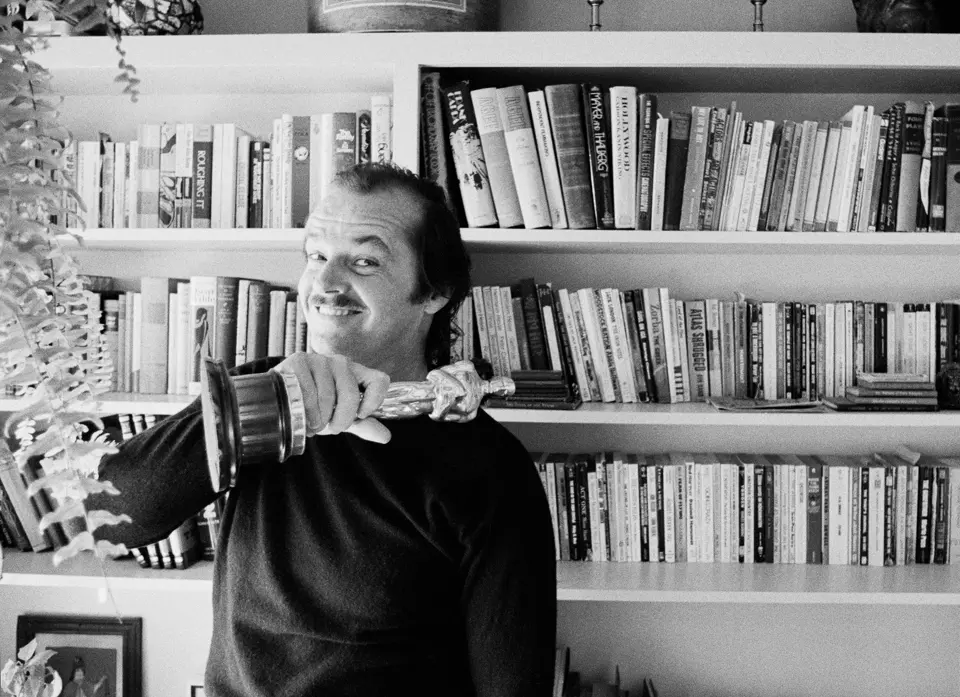 Black and white photograph of Jack Nicholson in front of a library of books.