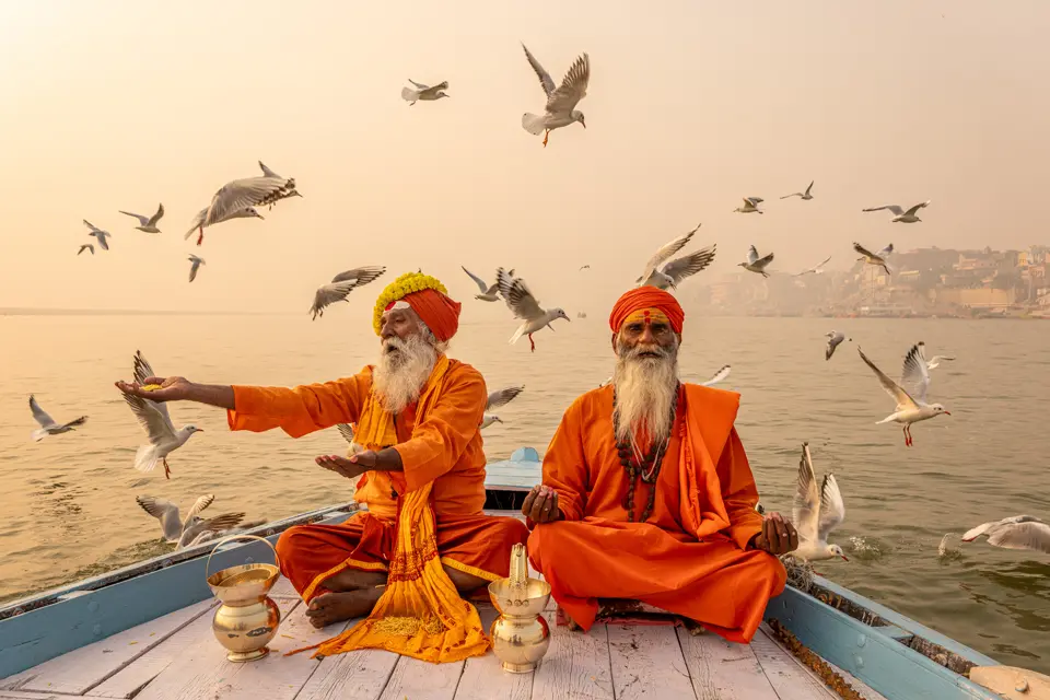 Two indian monks on a boat at sea surrounded by seagulls