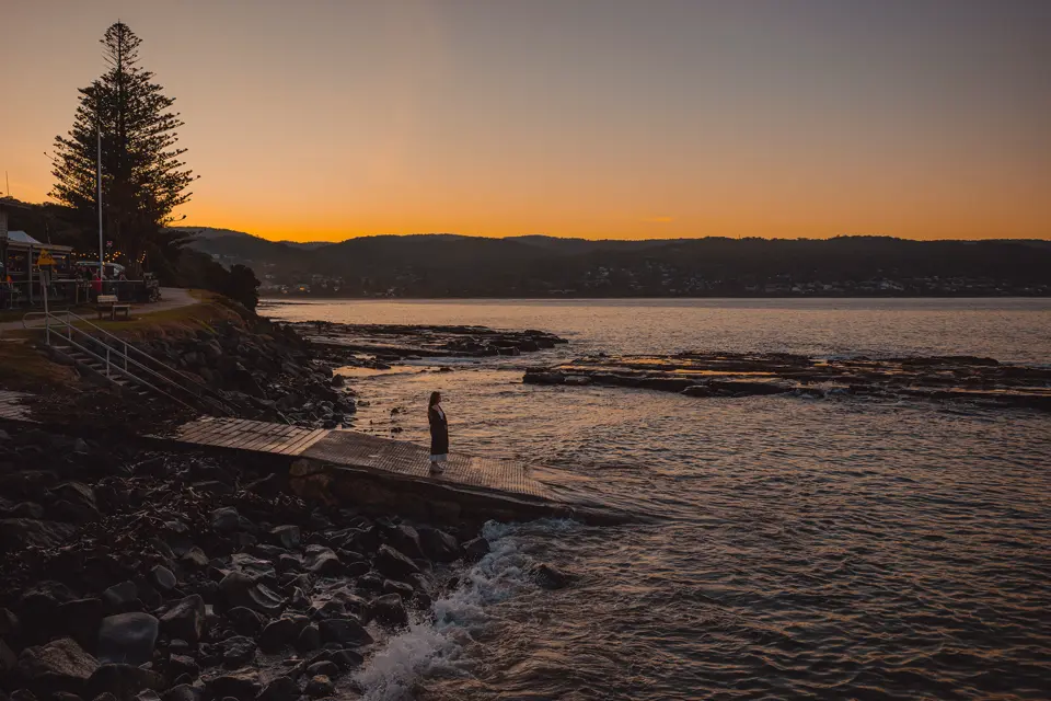 Woman standing on a jetty at the lake in the sunset