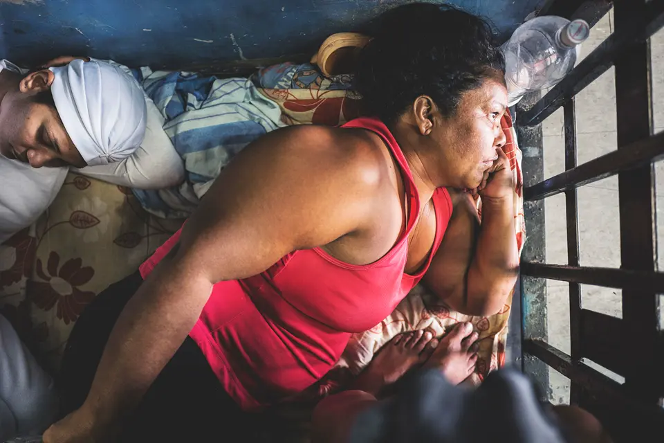 Venezuelan woman lies in a narrow room and looks out