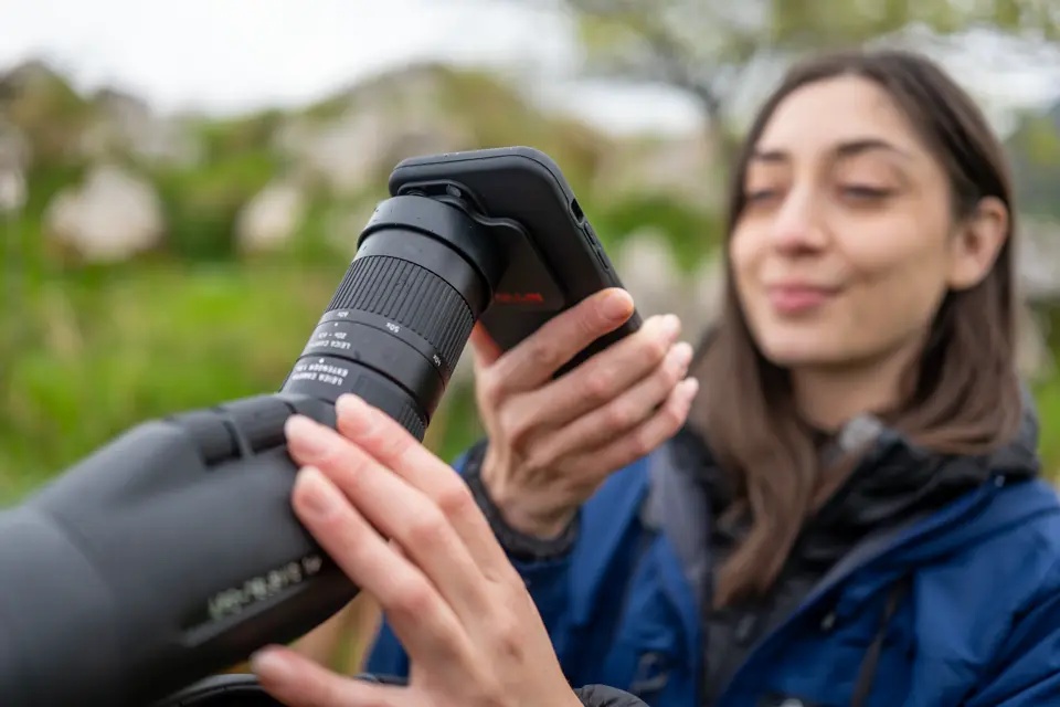 Woman is digiscoping with her smartphone and her Leica Televid spotting scopeSpotting scope
