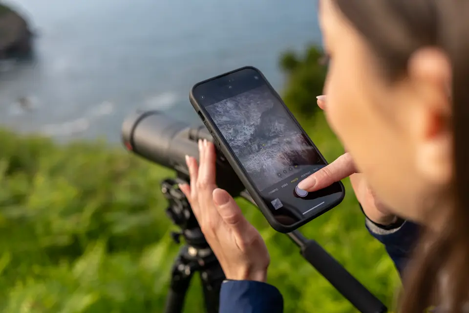 Woman is digiscoping with her smartphone and her Leica Televid HD spotting scope