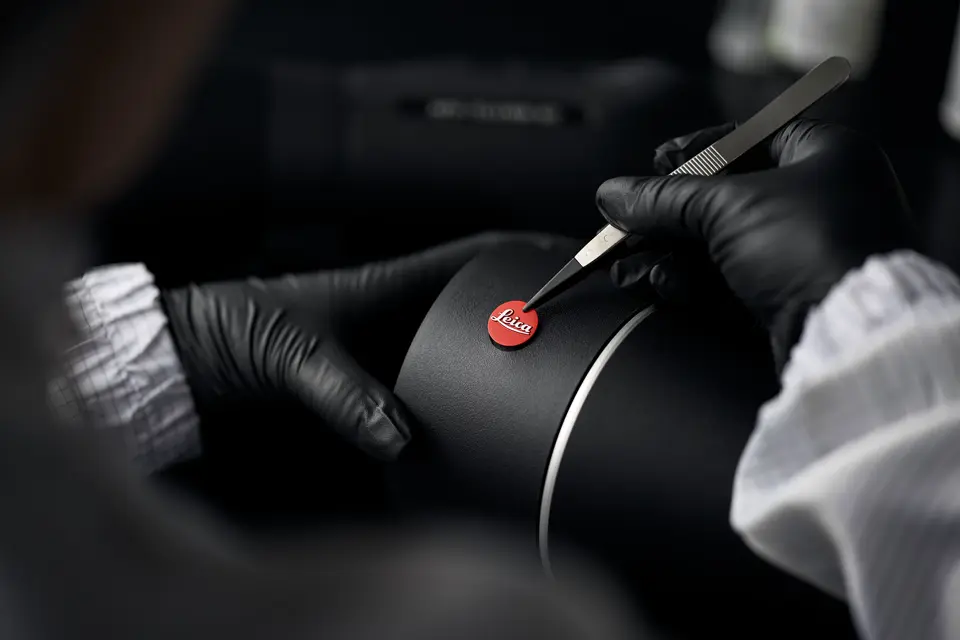 A Leica employee is sticking a Leica logo on the Leica spotting scope