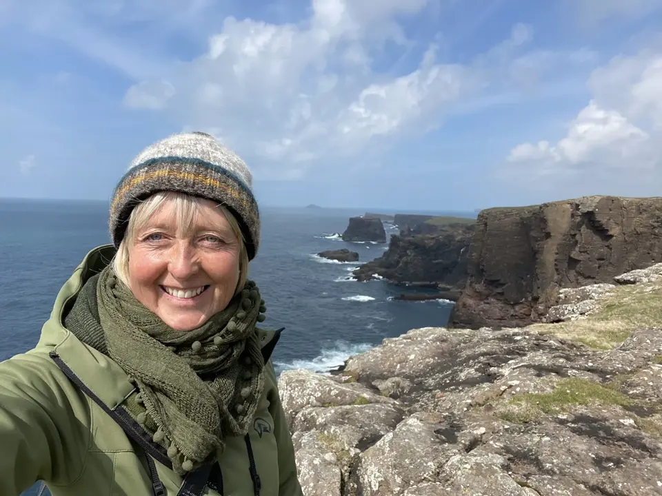 Image of WildlifeKate in a green coat in front of cliffs 
