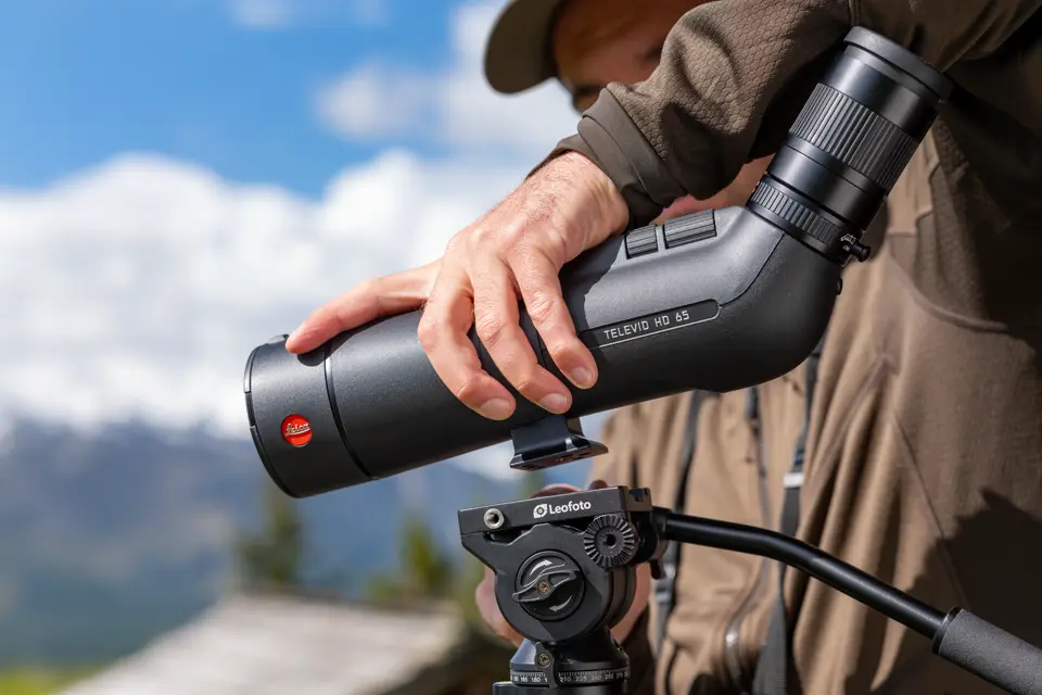 Man is putting his spotting scope on a tripod