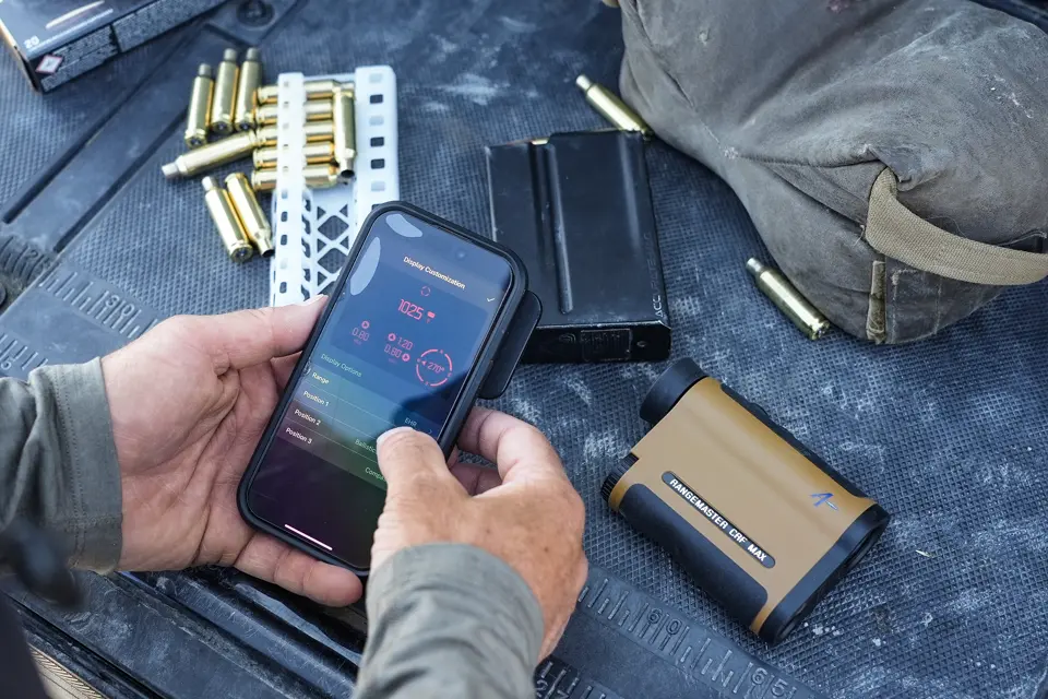 Man is checking his smartphone with Leica app and the Leica Rangemaster CRF MAX