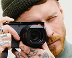 A man looks through a Leica camera while taking photographs.