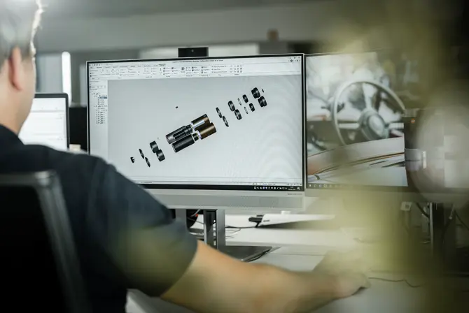 A worker creating a 3D render of the Leica binoculars on the computer