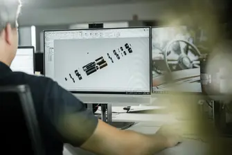 A worker creating a 3D render of the Leica binoculars on the computer