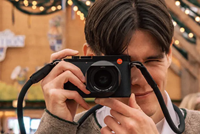 Close-up of Teo Crawford looking through a Leica Q3 viewfinder at Munich Oktoberfest, capturing authentic moments with a compact full-frame camera.