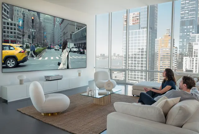 A woman and man sitting on a couch watching a Leica Cine 1 projection.