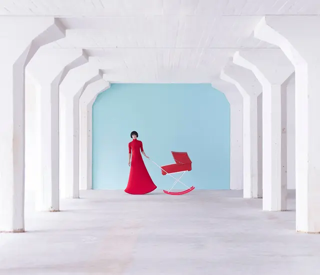 Woman in red with a red pram in front of a white background