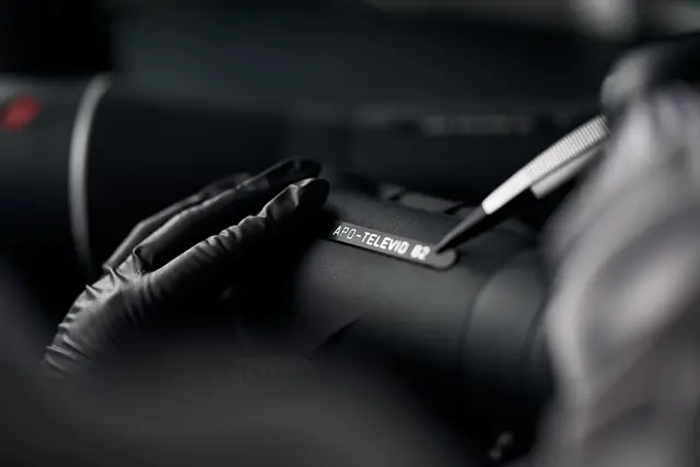 A Leica employee is sticking a Leica product name batch on the Leica spotting scope