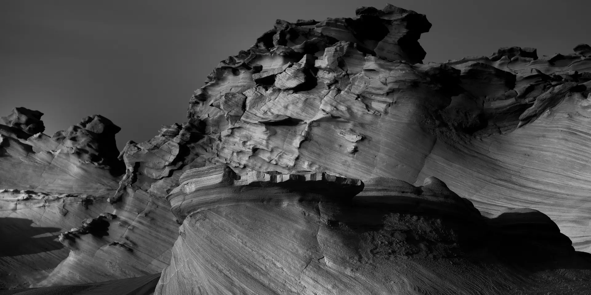 Black and white photography of jagged rock formations in a barren landscape