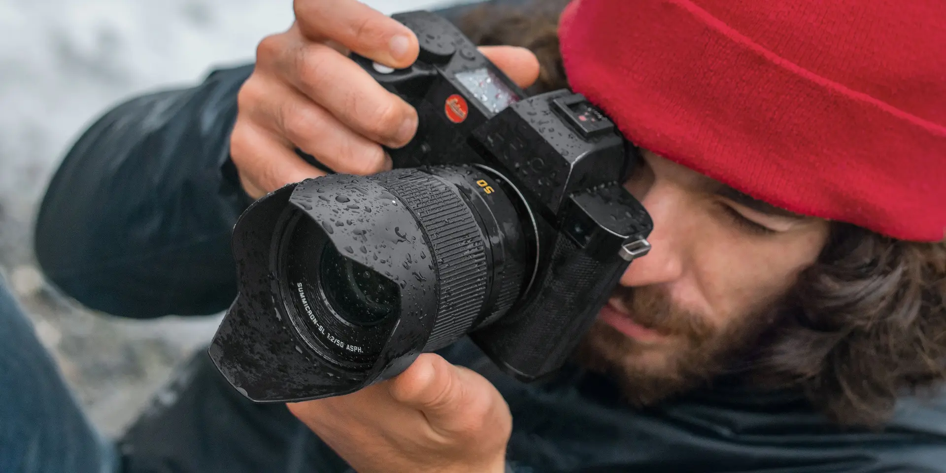Close-up of a photographer with a red cap looking through the camera