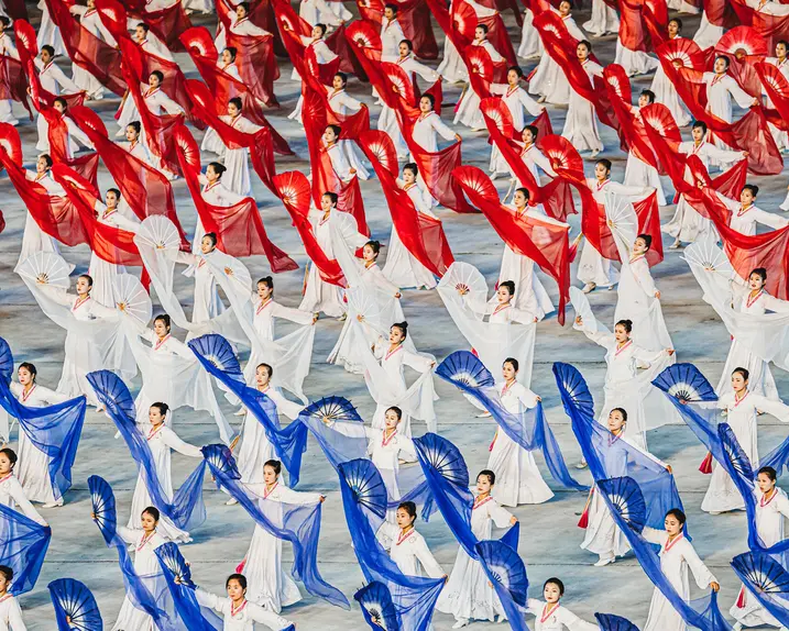 North Korean women dance with hand fans and transparent cloths in white, red and blue. 