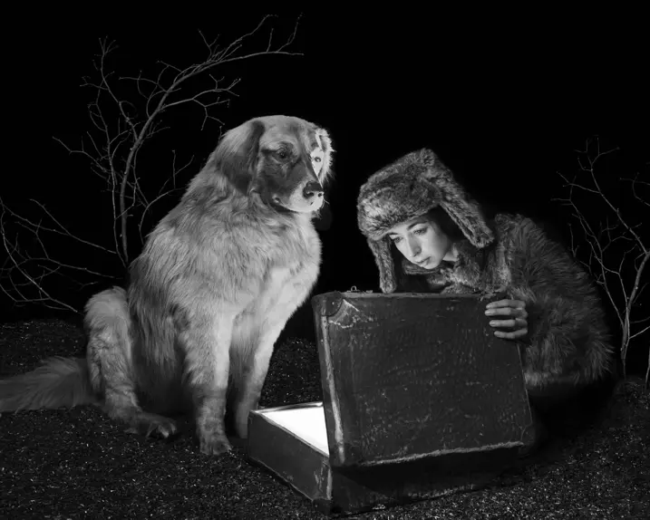Viktoria Sorochinski and a dog looking into an old suitcase that is glowing inside. 