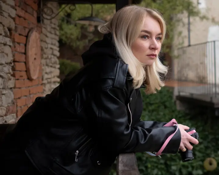 Woman on a balcony holding a camera in her hands.