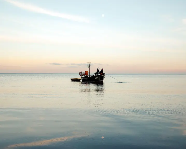 A person in a small boat fishing in the sea.
