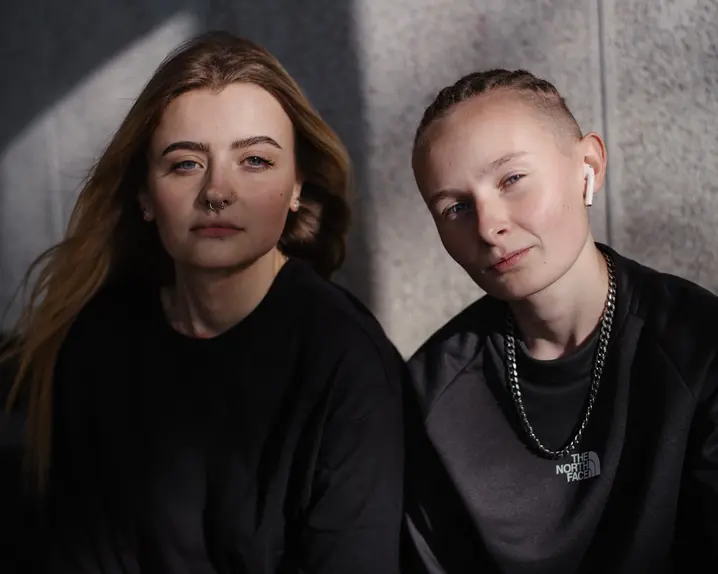 Two women sitting together and looking directly at the camera.