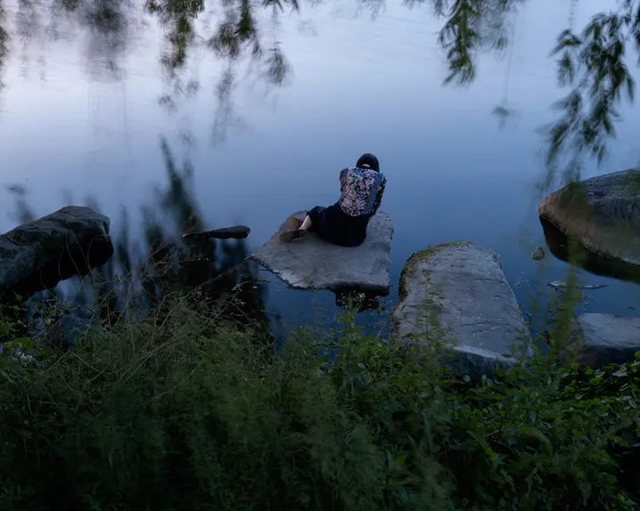 Woman sitting on a stone by the lake