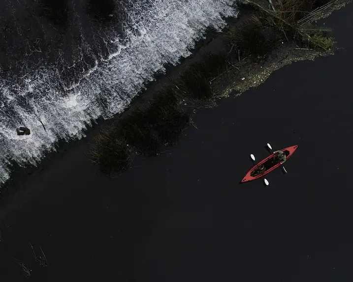 Red canoe paddling along the black sea coast.