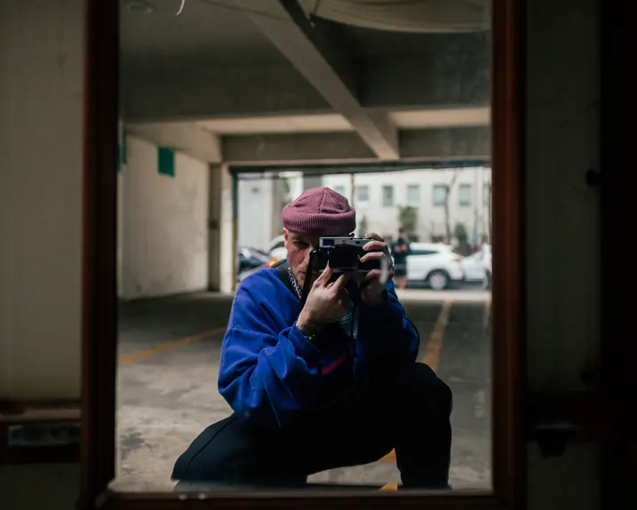 A man takes a picture of himself in a mirror in a garage.