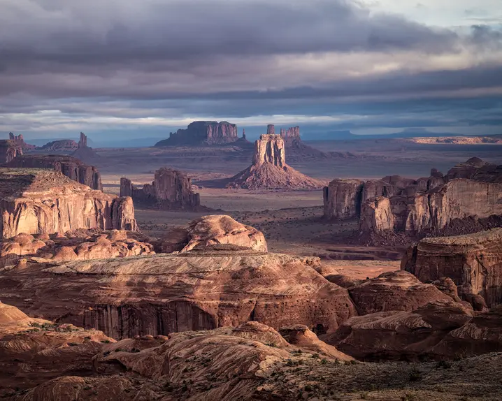 Vast desert landscape with remarkable rock formations under a cloudy sky.