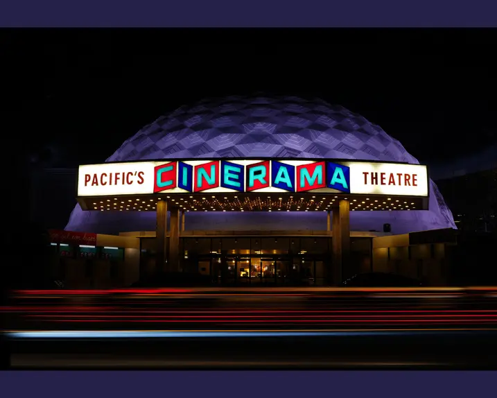 Luminous Cinerama theatre at night.