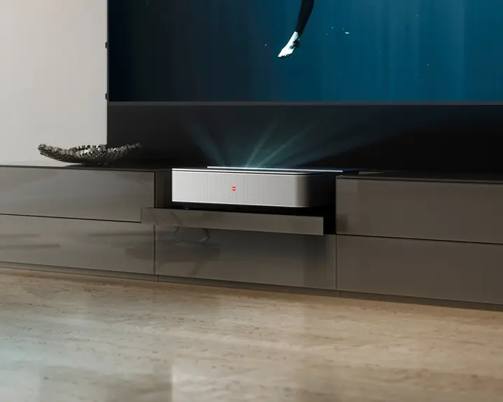 A Leica projector in a gleaming TV cabinet in a living room projects an image onto a screen.