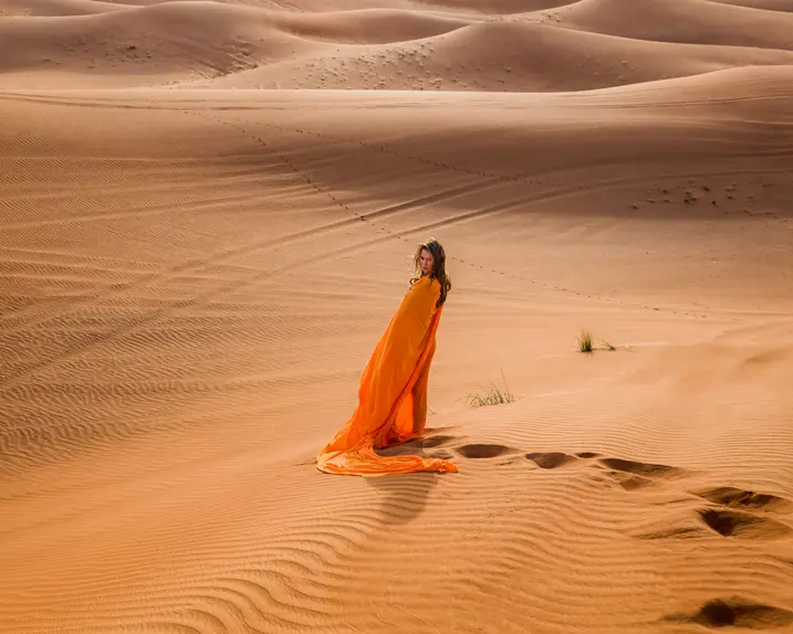 Woman in an orange dress standing in the desert.
