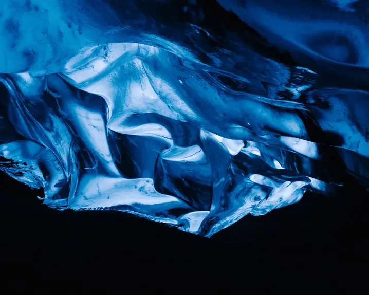 A glowing blue ice formation in a dark cave.