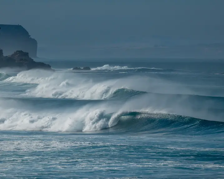 Waves breaking on a coastline under a blue sky