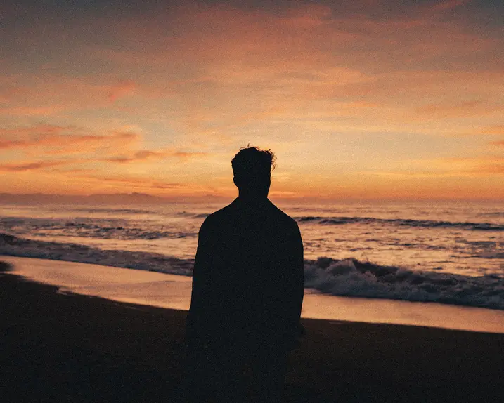 Silhouette of a man watching the sunset on the beach.