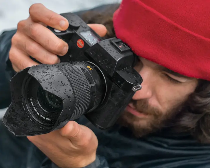 Close-up of a photographer with a red cap looking through the camera