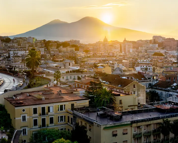 Italian city and the sun setting behind a mountain.