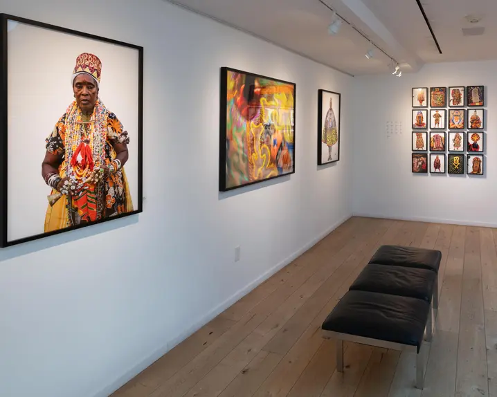Gallery with colourful portraits of people in traditional dress from different cultures, wooden floor and modern bench seat.