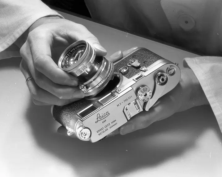 Man mounts lens on Leica M3