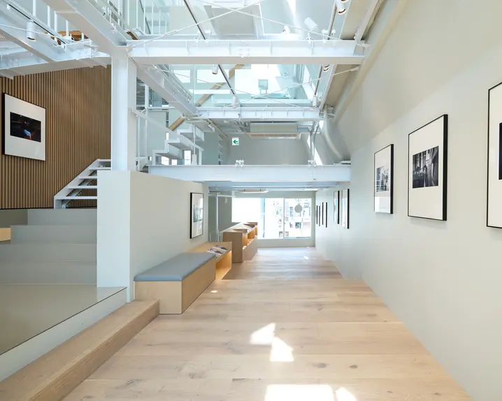 Bright, modern room with stairs, wooden floor and framed black and white photos.